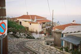 Smal straatje met stenen huizen in Kosmadaioi, Samos, met zeezicht.